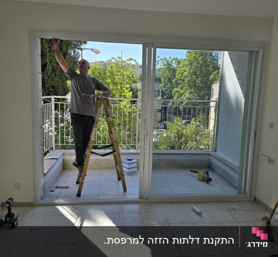 אדם עובד על מסגרת אלומיניום של דלת הזזה